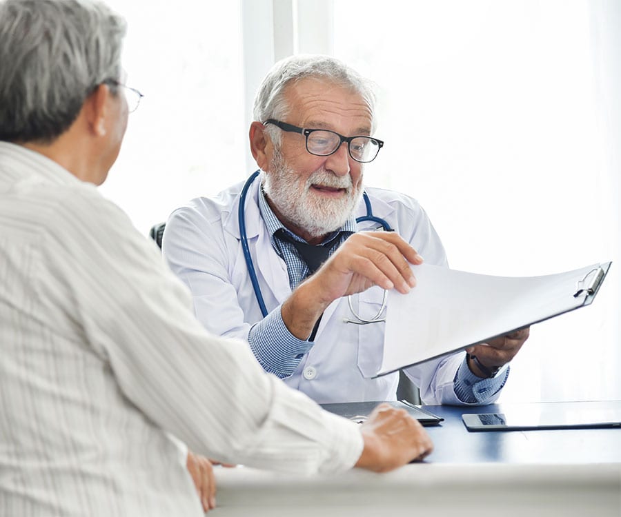 Physician-Services - Seasons Hospice MO | End of Life Care | Springfield, MO A doctor explains a plan of care to his patient in a pleasant exchange.