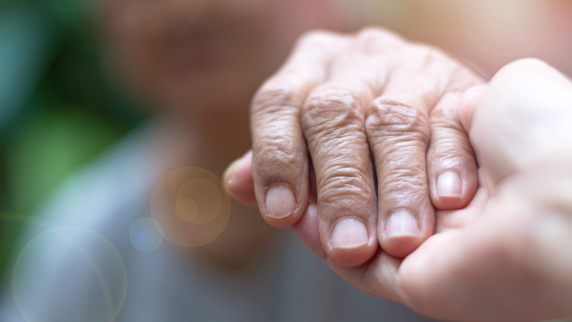 A hospice caregiver holds the hand of a patient. One of the benefits of hospice care is the support you receive.